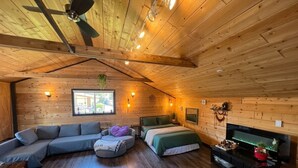 A cozy room with a wooden ceiling, a sofa, a bed, a TV, and a window. - Charming "Melrose Place" w Year-Round Heated Pool, Deck & Grill (Victoria)