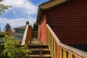 A wooden deck leading to a red building with a gable roof and a visible chimney. - Charming "Melrose Place" w Year-Round Heated Pool, Deck & Grill (Victoria)