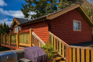 A red wooden cabin with a covered grill, wooden deck, and a satellite dish. - Charming "Melrose Place" w Year-Round Heated Pool, Deck & Grill (Victoria)