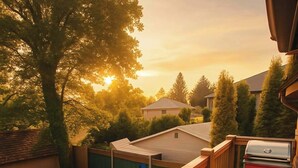 A wooden deck with a barbecue grill, a swimming pool, and a view of houses and trees. - Charming "Melrose Place" w Year-Round Heated Pool, Deck & Grill (Victoria)