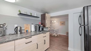 A modern kitchen with a marble countertop, built-in appliances, and a dining area with a small table and chairs. - Quaint 1 Bedroom Suite, Victoria, BC (Victoria)