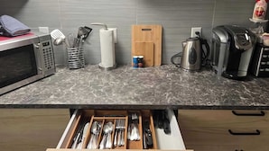 A kitchen with a microwave, toaster, coffee maker, and a drawer with utensils. - Quaint 1 Bedroom Suite, Victoria, BC (Victoria)