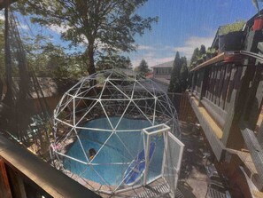 A view through a window with a geometric structure, possibly a sculpture, and a pool. - Quaint Attic Suite w/ Heated Pool (Year-Round) (Victoria)