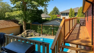Ein Garten mit Swimmingpool, Grill und Holzterrasse.