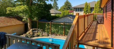 A backyard with a swimming pool, a barbecue grill, and a wooden deck.