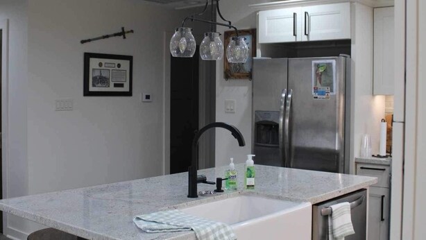 Una cocina moderna con una isla central, electrodomésticos de acero inoxidable y una lámpara colgante.
