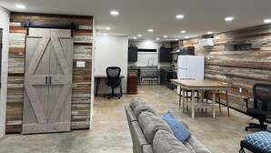 Una cocina moderna con un detalle de pared de madera, una zona de comedor con mesa y sillas, y un amplio ventanal corredero.