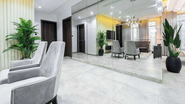 A modern lobby with a seating area, a large mirror reflecting the interior, and potted plants. - The Azaria Hotel and Apartments (Lekki)