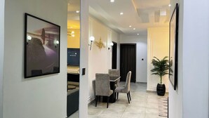 A modern hallway with a dining area, a large framed artwork, recessed ceiling lights, and a potted plant. - The Azaria Hotel and Apartments (Lekki)