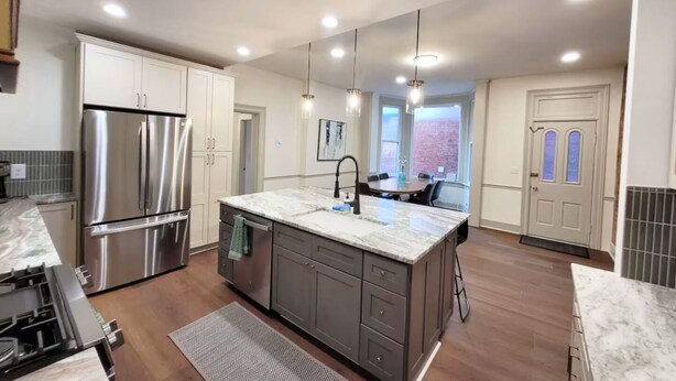 A modern kitchen with a large island, stainless steel appliances, and pendant lighting.