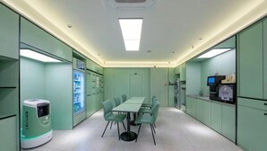 A conference room with a table and chairs, a vending machine, and a refrigerator.