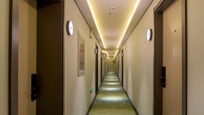 A hotel hallway with doors on both sides, a carpeted floor, and overhead lighting.