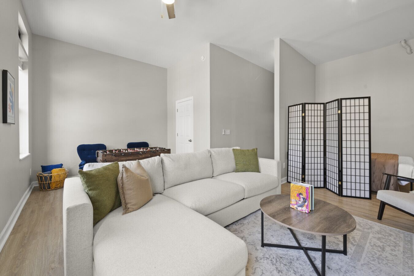 A modern living room with a sectional sofa, a coffee table, and a traditional Japanese room divider.