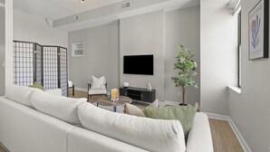 A modern living room with a sofa, a coffee table, a TV, and a plant.