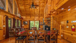 L’intérieur d’un chalet en bois comprend un coin repas, un plancher en bois et une cheminée.