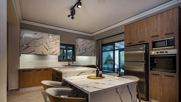 A modern kitchen with marble countertops, wooden cabinets, and stainless steel appliances. - Eleonas Private Pool Villa (Artemisia)