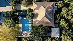 An aerial view of a property with a swimming pool, a large wooden deck, and dense surrounding vegetation. - Eleonas Private Pool Villa (Artemisia)