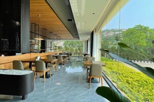 A modern interior with a bar area, seating, and a view of greenery.