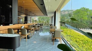 Un restaurante moderno con barra, asientos y vistas a zonas verdes.