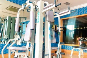 Un gimnasio con equipo de ejercicio, espejos y un ventanal con vistas al exterior.