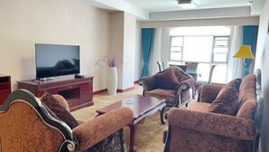 Una sala de estar con televisor de pantalla plana, una mesa de centro y dos sofás.