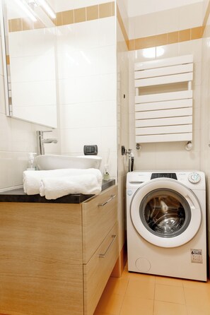 A modern bathroom with a sink, mirror, towel rack, and a front-loading washing machine. - Charming Two Bedroom Private Apartment (Venezia)