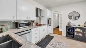 Una cocina moderna con armarios blancos, una campana extractora de acero inoxidable, microondas y horno integrado.