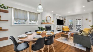 Una sala moderna con chimenea, un comedor con mesa y sillas de madera, y un sofá.