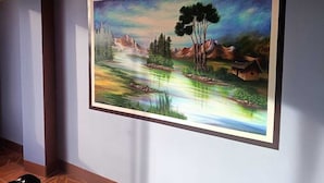 A mural of a landscape with mountains, trees, and a house by a river. - Nexus Mirasol Backpackers (Copacabana)