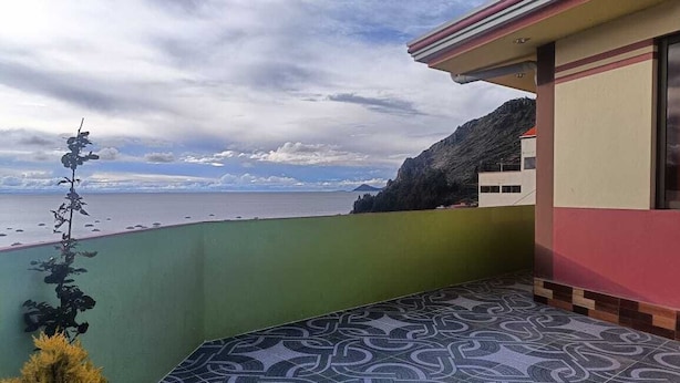 A balcony with patterned flooring, a view of the sea, and a building with a red and beige facade. - Nexus Mirasol Backpackers (Copacabana)