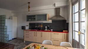 Una cocina moderna con comedor, que incluye una mesa de madera con alimentos para el desayuno, un microondas integrado y una encimera roja.