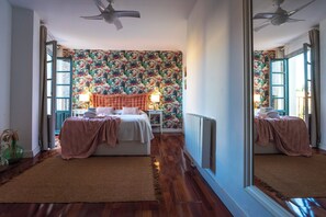 A bedroom with a floral wallpaper, a tufted headboard, a large mirror, and a ceiling fan. - Las Vistas Residence - Best Views in Ronda (Ronda)
