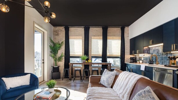 Een moderne woonkamer met een bank, een salontafel en een eethoek met een tafel en stoelen.
