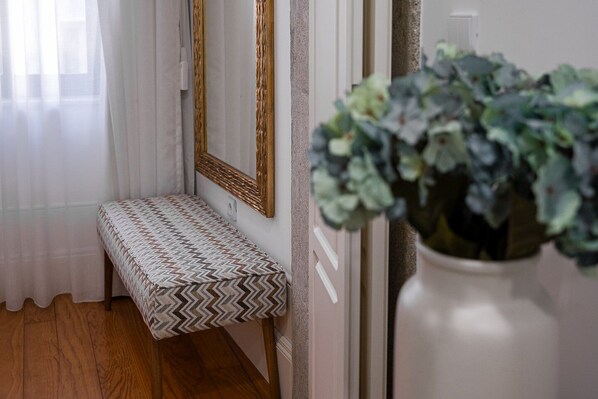 A hallway with a bench, a mirror, and a potted plant.