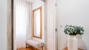 A hallway with a bench, a mirror, and a vase with flowers. - GuestReady - Lovely heaven in Porto (Porto)