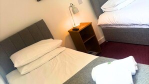 Una habitación de hotel con una cama, una mesita de noche, una lámpara y una alfombra roja.