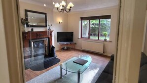 A living room with a glass coffee table, a TV, and a fireplace. - Mulberry House - Modern Family Retreat (Sligo)