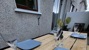 A wooden outdoor table set with a blue plate, a fork, and two wine glasses. - Mulberry House - Modern Family Retreat (Sligo)