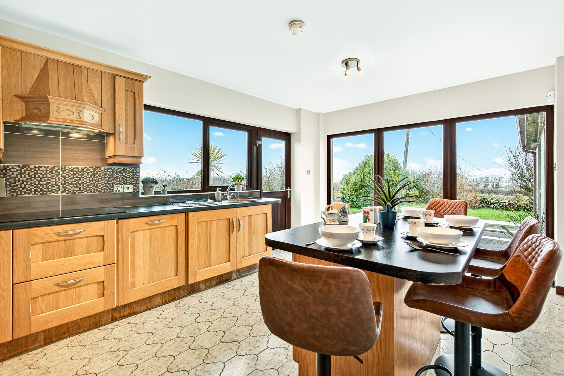 A modern kitchen with wooden cabinets, a black countertop, and a dining area with a table set for four.