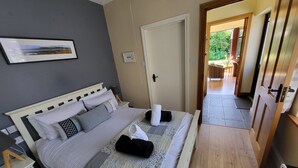 Una cama bien hecha con una manta a cuadros, una mesita de noche con una lámpara y un cuadro en la pared.