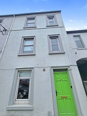 A multi-story building with a green door and white-framed windows. - Wolfe Tone (Sligo)