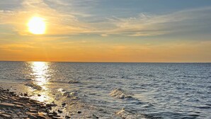 A sunset over a calm sea with a rocky shoreline. - Lakefront Escape | Fire Pit, Pets & Scenic Views (Sturgeon Bay)