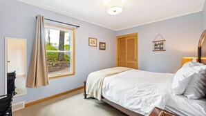 A bedroom with a bed, a window with curtains, a bedside lamp, and a door. - Lakefront Escape | Fire Pit, Pets & Scenic Views (Sturgeon Bay)