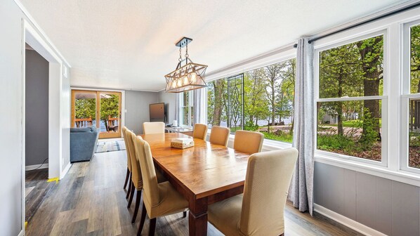 A dining area with a large wooden table, six chairs, and a chandelier.