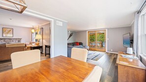 Uma sala de estar moderna com uma mesa de jantar de madeira, um sofá e uma TV.