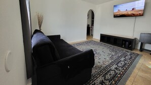 A living room with a black sofa, a patterned rug, a flat-screen TV, and a fireplace. - Large parking lot/sleeps 8 (Laredo)