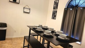 A dining table with multiple plates and bowls, a trash can, and a bench. - Large parking lot/sleeps 8 (Laredo)