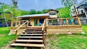Ein zweistöckiges Holzhaus mit grüner Tür und einer Holztreppe zum Hauseingang.