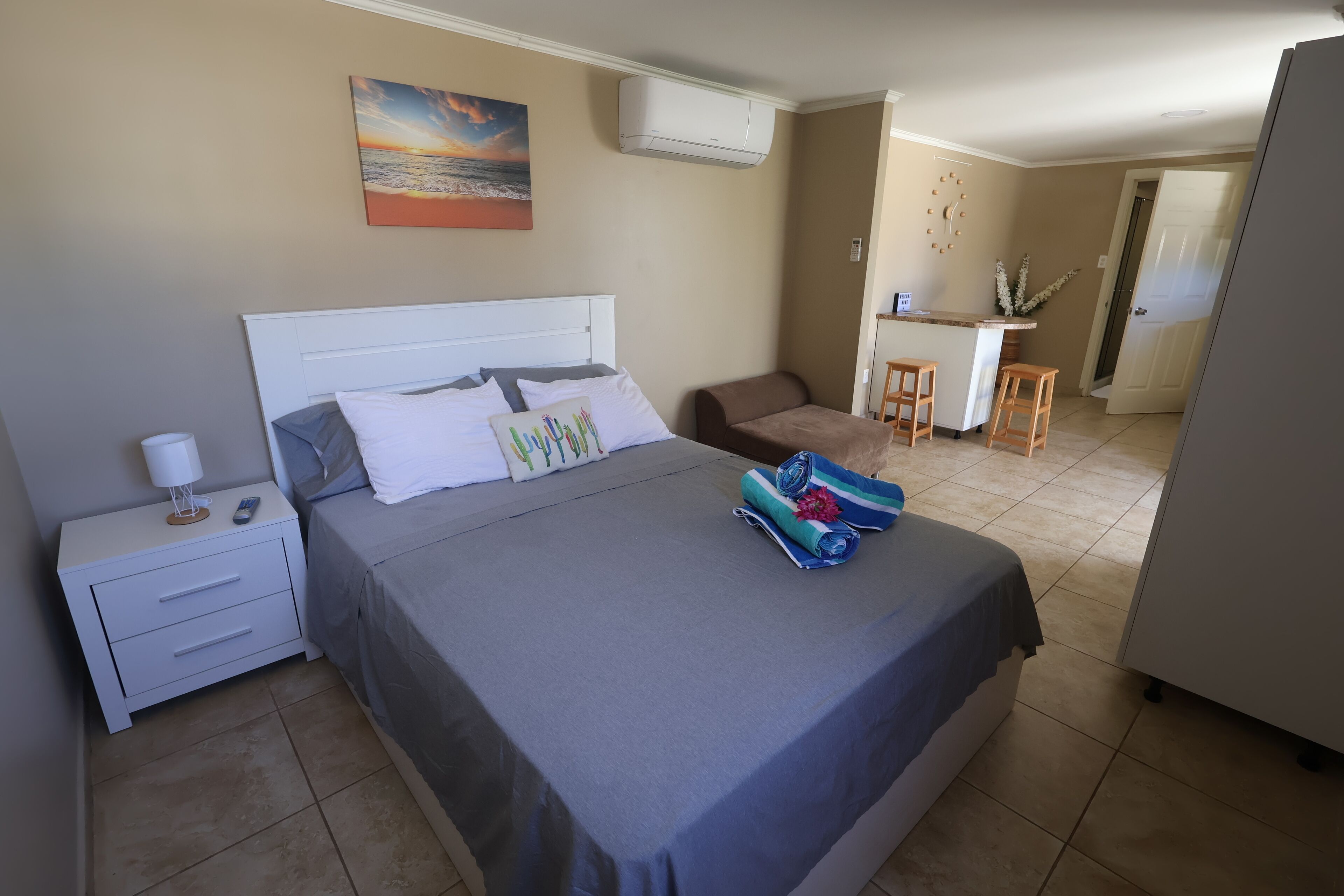 A bedroom with a bed, bedside table, and a desk area with chairs.