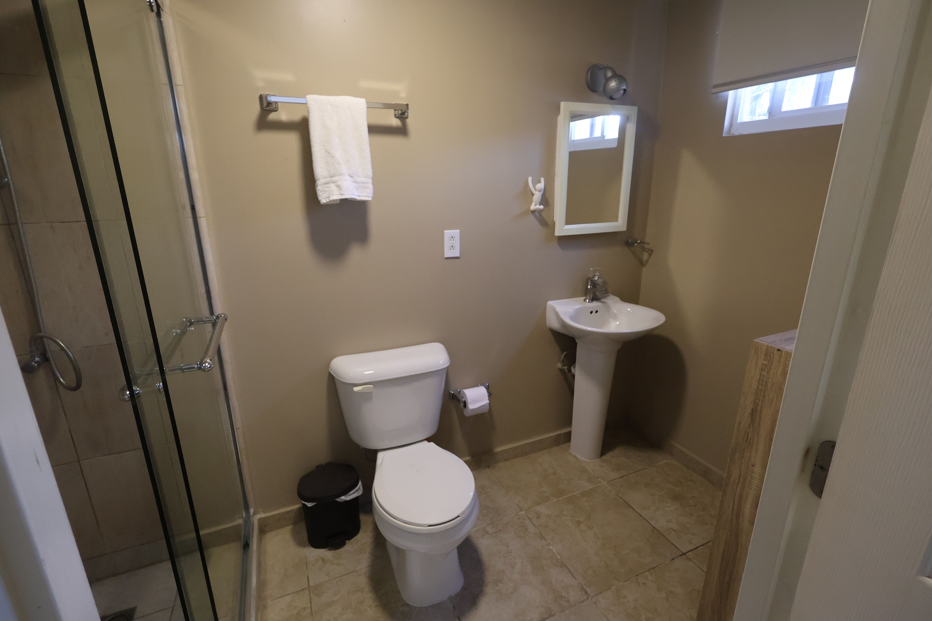 A bathroom with a toilet, sink, and glass shower enclosure.
